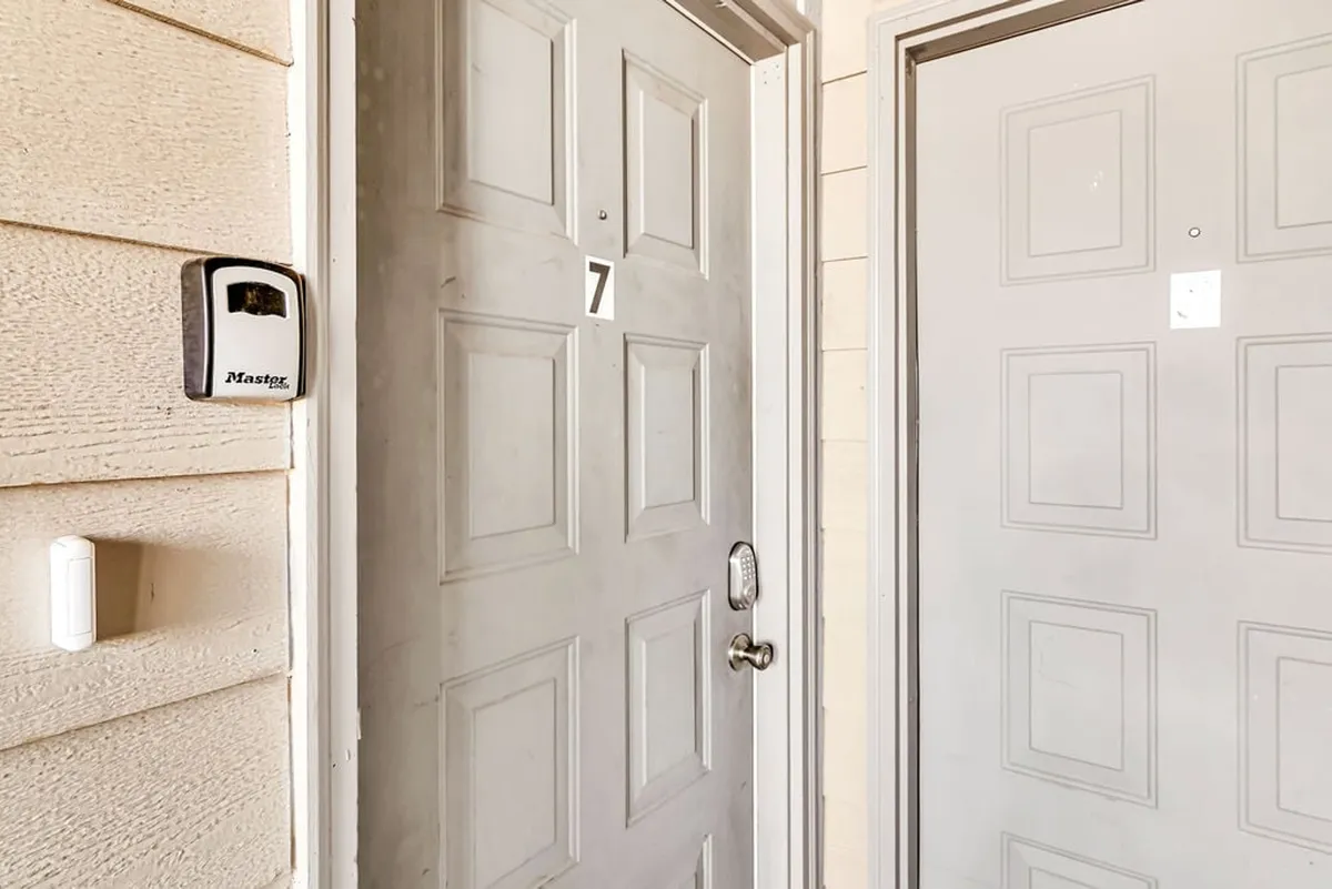 A close-up of a modern entry door, featuring a door number, sturdy handle, and a keypad lock. The scene suggests easy, accessible entry for all guests, setting a tone of welcome and security.