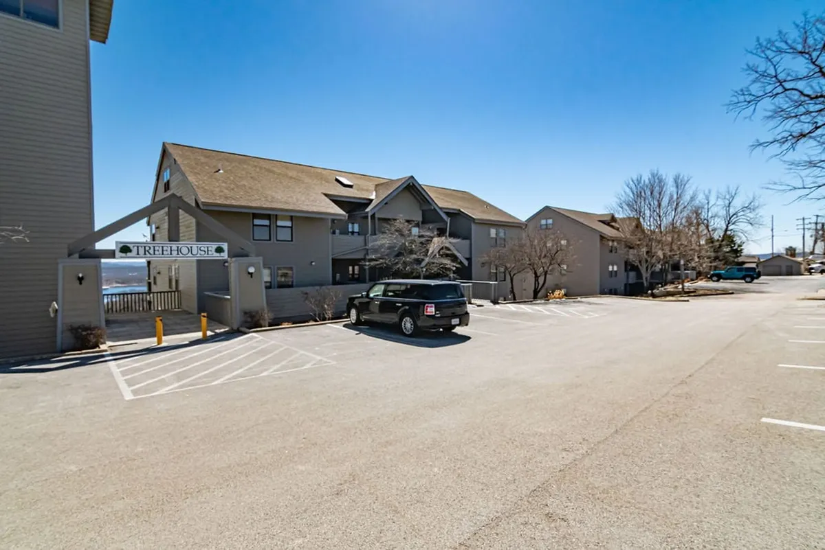 This welcoming exterior shows the Treehouse sign and unique building architecture, as well as the surrounding parking area and entry path. The inviting entrance hints at a comfortable stay and highlights the property’s connection to surrounding nature and easy access for exploring.